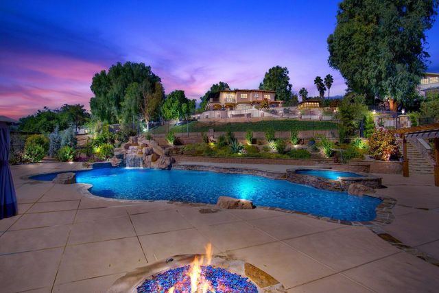 Backyard pool with fire pit at dusk