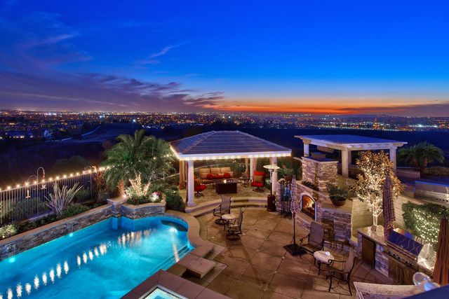 Backyard patio with pool, pergola and city lights at twilight