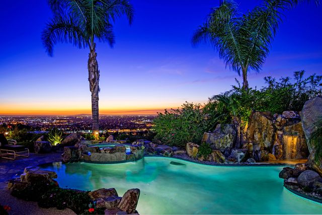 Pool with palm trees and waterfall at sunset