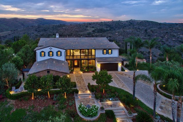Aerial view of a two-story home surrounded by hills at dusk