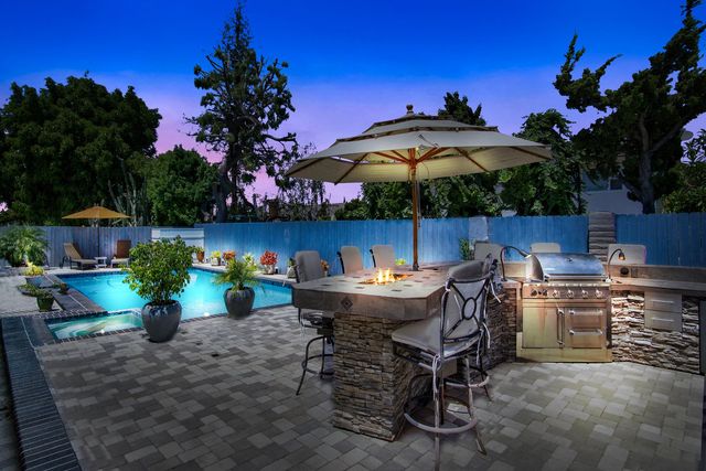 Backyard outdoor kitchen and pool terrace at twilight