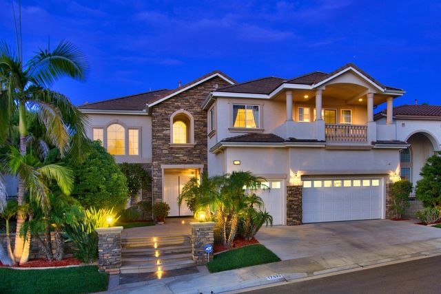 Two-story home with front steps and palm trees at twilight