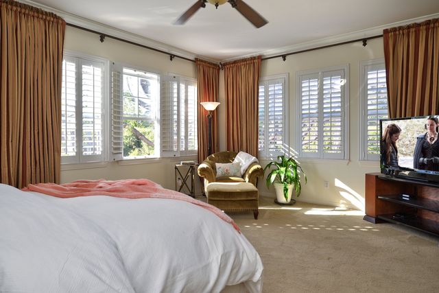 Bedroom with plantation shutters and drapes