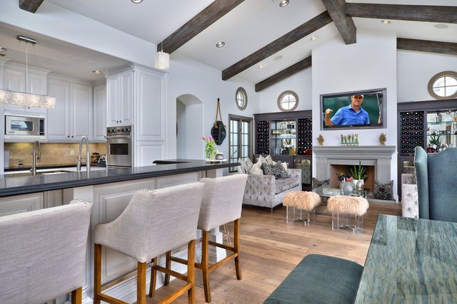 Open kitchen with white cabinets and wood beams