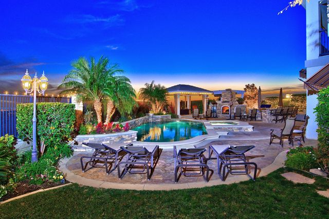 Backyard with pool lounge chairs and palm trees at twilight