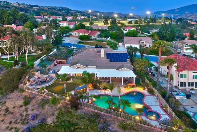 Aerial view of a hillside home with pool at dusk