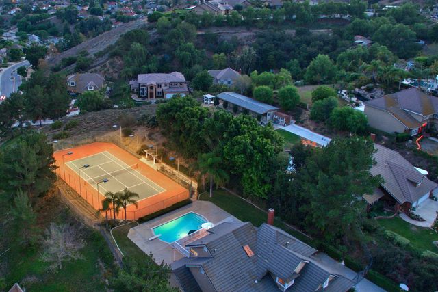 Aerial view of a home with tennis court at dusk