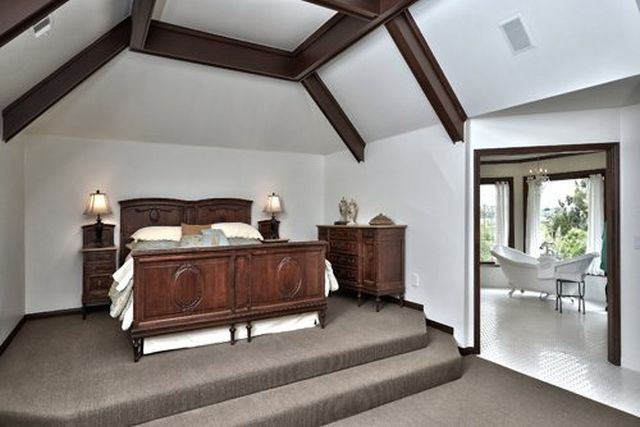 Bedroom with dark wood bed and vaulted beamed ceiling